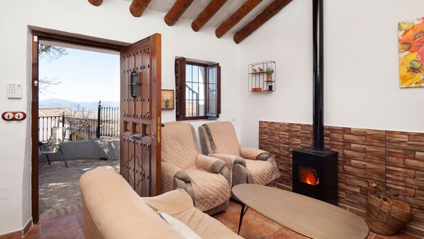 A cozy living room with a sofa, armchairs, a table, a fireplace, and a view of the outdoors.