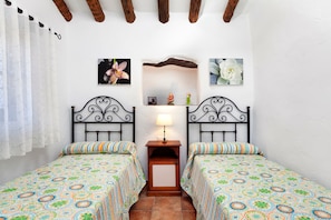 Un dormitorio con dos camas, una mesita de noche con lámpara y adornos en la pared.