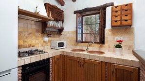 A kitchen with a gas stove, microwave, sink, wooden cabinets, and a window with a view.