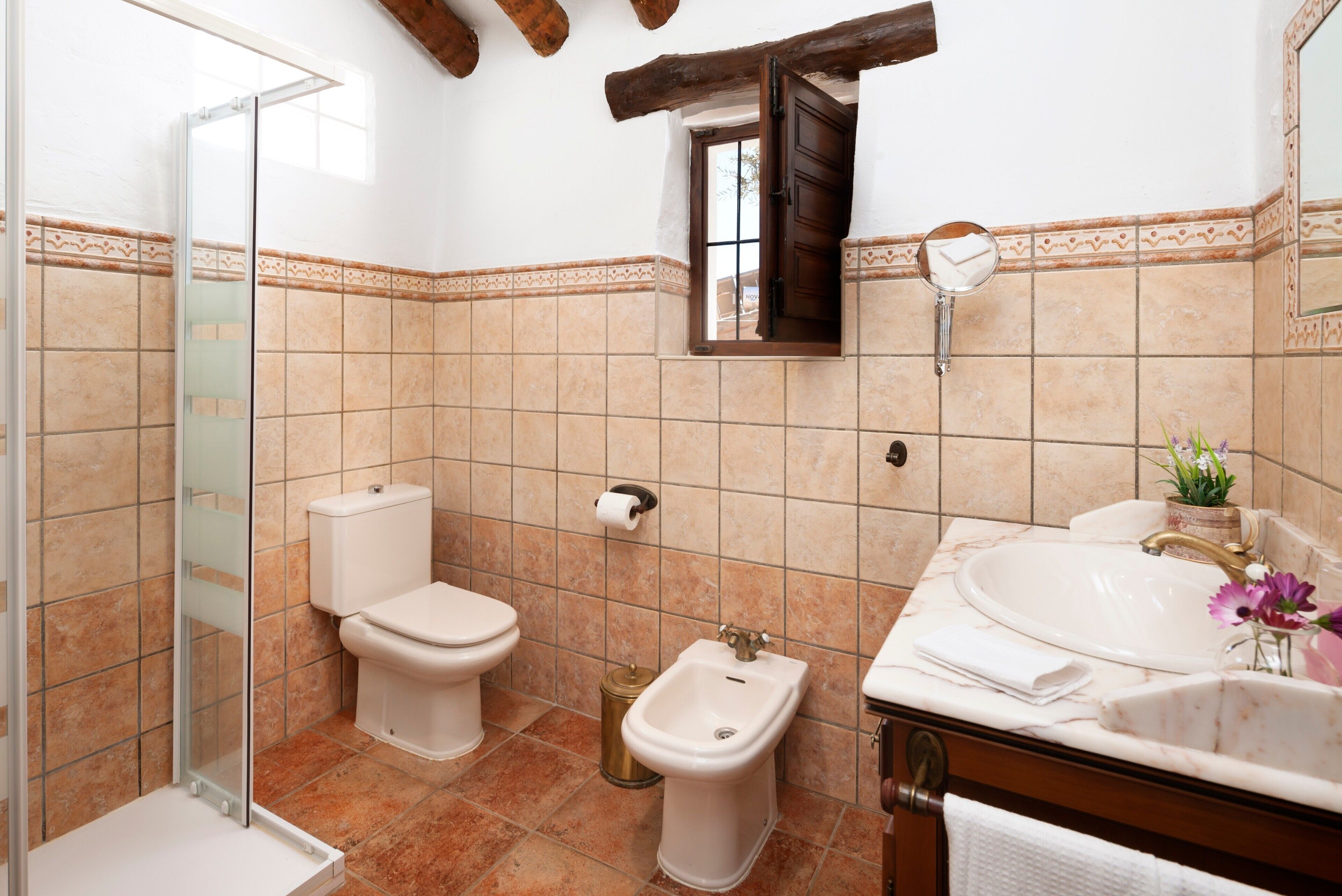 Une salle de bain comprenant des toilettes, un bidet, un lavabo et une douche à parois de verre.
