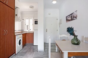 Une cuisine équipée d’un lave-linge, d’une table à manger avec des chaises et d’un vase avec une plante.