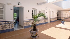 A corridor with a potted plant, tiled walls, and a clock.