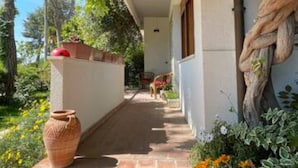 A covered outdoor corridor with a tiled floor, a large pot, and a rope wrapped around a tree. - Apartment 'Via Verdi 14' with Sea View, Shared Terrace and Wi-Fi (Mondolfo)