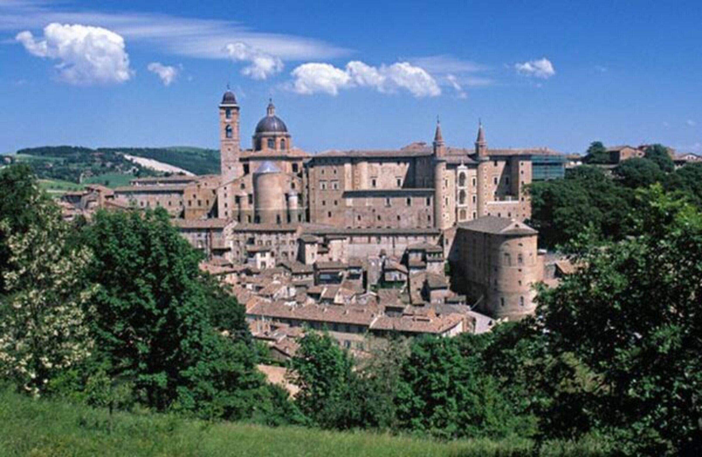 Un bâtiment historique doté de nombreuses tours et de coupoles, entouré de verdure.
