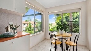 Cozinha moderna com área de refeições, janelas amplas e vista para uma área residencial.