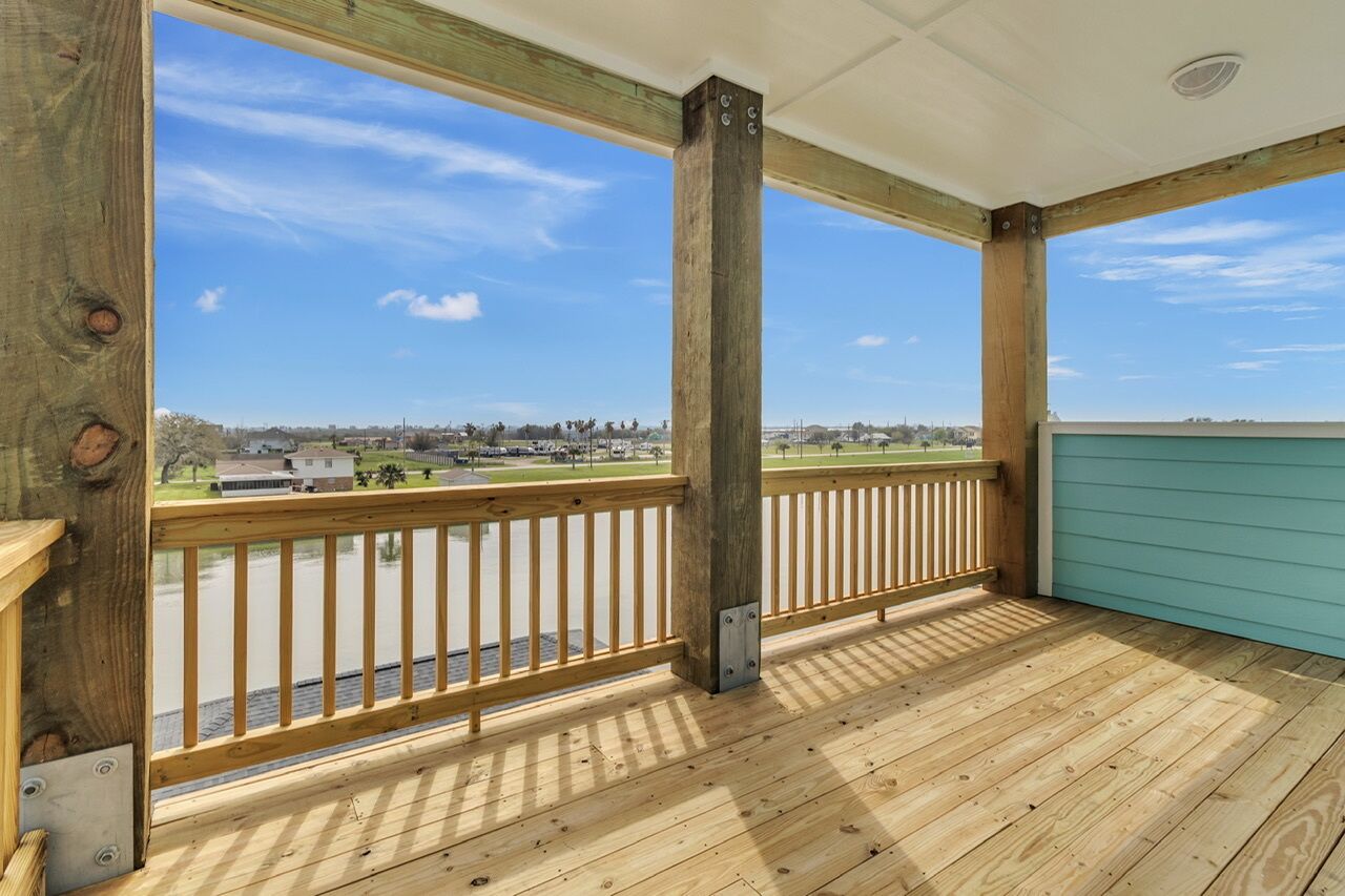 Une terrasse en bois offrant une vue sur une rivière et des bâtiments situés au loin.