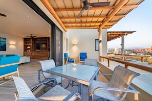 A modern outdoor patio with a glass-top table, metal chairs, and a wooden ceiling. - Penthouse | Views + Beach Access + Rooftop Terrace (Huatulco)