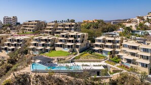 A modern hotel complex with multiple buildings, a central swimming pool, and landscaped gardens. - Penthouse | Views + Beach Access + Rooftop Terrace (Huatulco)