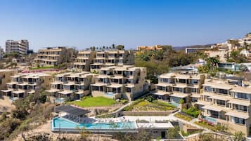 A modern hotel complex with multiple buildings, a central swimming pool, and landscaped gardens.
