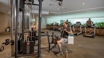 Un gimnasio con equipo de ejercicio, cintas de correr y una zona de pesas.