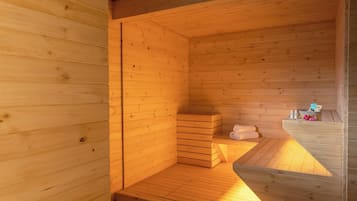 A wooden sauna with benches, towels, and toiletries on a wooden platform.