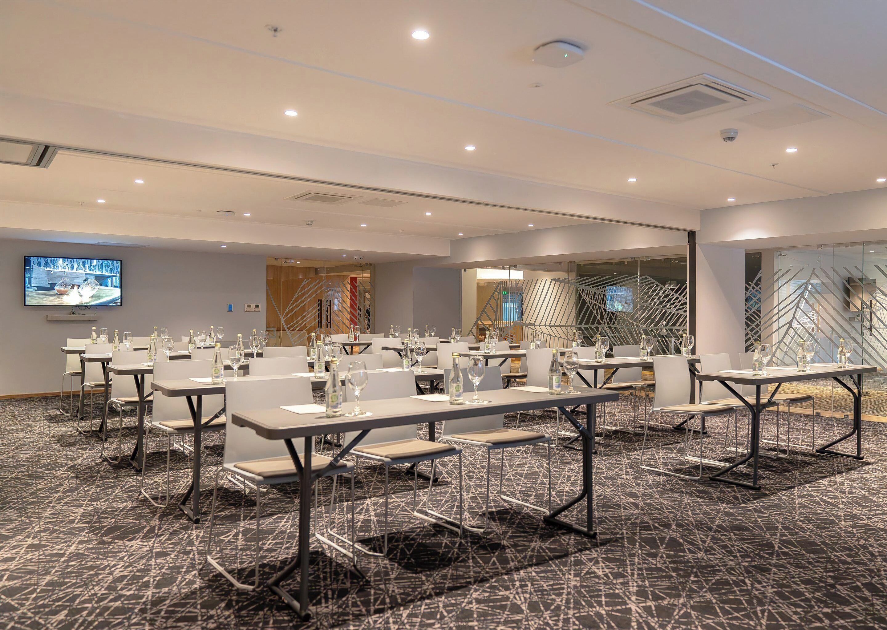 A conference room with tables set for a meeting, equipped with water bottles and glasses.