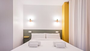 Une chambre d’hôtel comprenant un lit, deux tables de chevet et deux lampes fixées au mur.