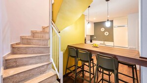 Une cuisine moderne avec un îlot central en bois, des tabourets de bar et des luminaires suspendus.