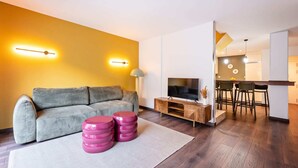 Un salon moderne avec un canapé, un téléviseur et des tabourets décoratifs.