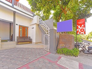 Entrada de hotel con una escalera, un banco y un cartel.