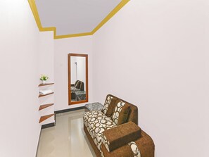 Una habitación con un sofá, un espejo y una planta en maceta.