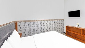 Un dormitorio con cama, cómoda de madera, televisor de pantalla plana y un panel decorativo en la pared.