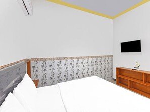 Un dormitorio con cama, cómoda de madera, televisor de pantalla plana y un panel decorativo en la pared.