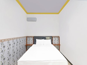 Una cama individual con colchón blanco y cabecera estampada con motivos florales.