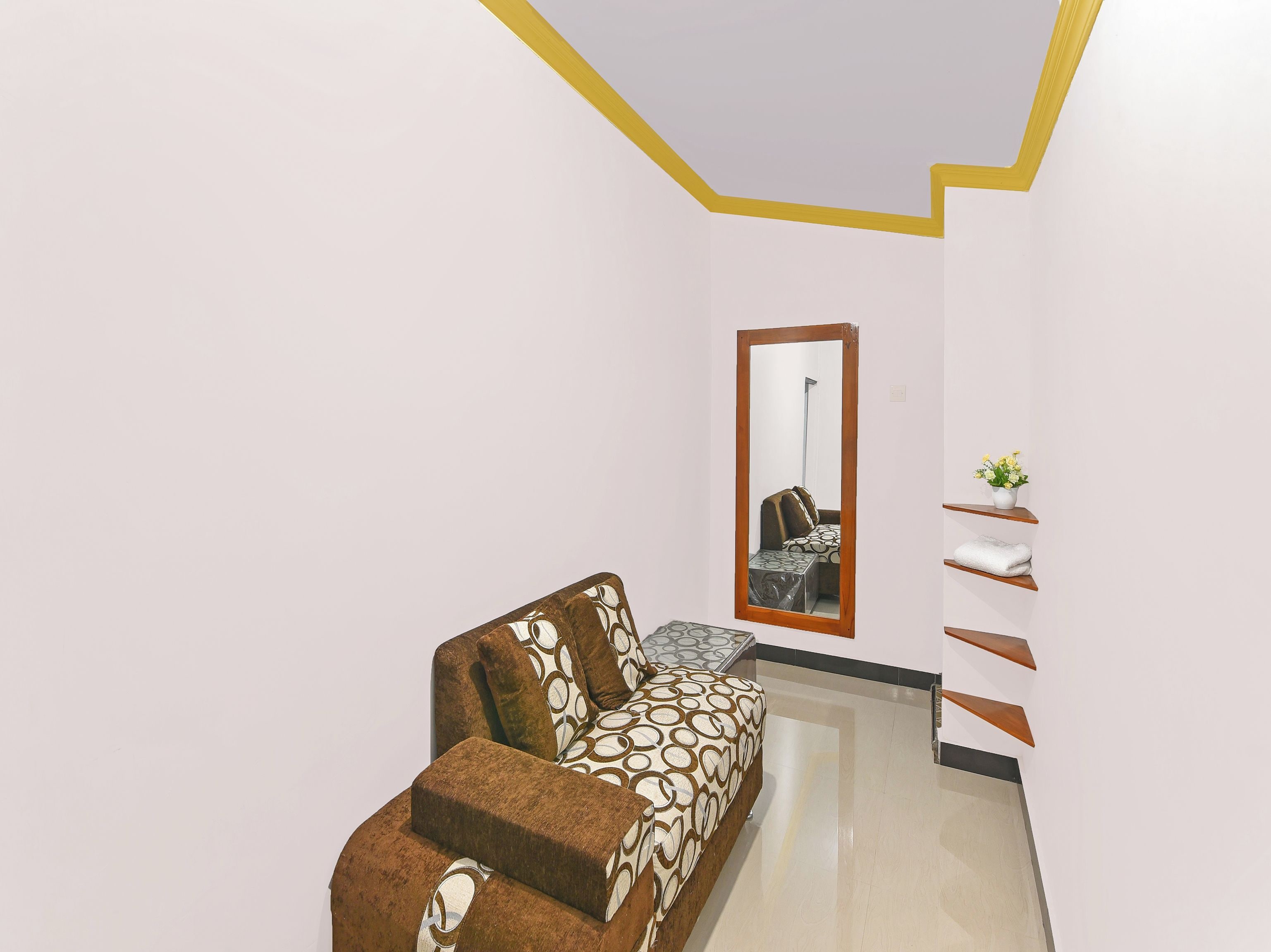 Ein modernes Interieur mit einer Couch, einem Spiegel und einer kleinen Pflanze.