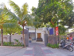 A modern building with a staircase leading to a door, surrounded by palm trees and a paved walkway. - OYO 91192 Homestay Antara (Melaya)