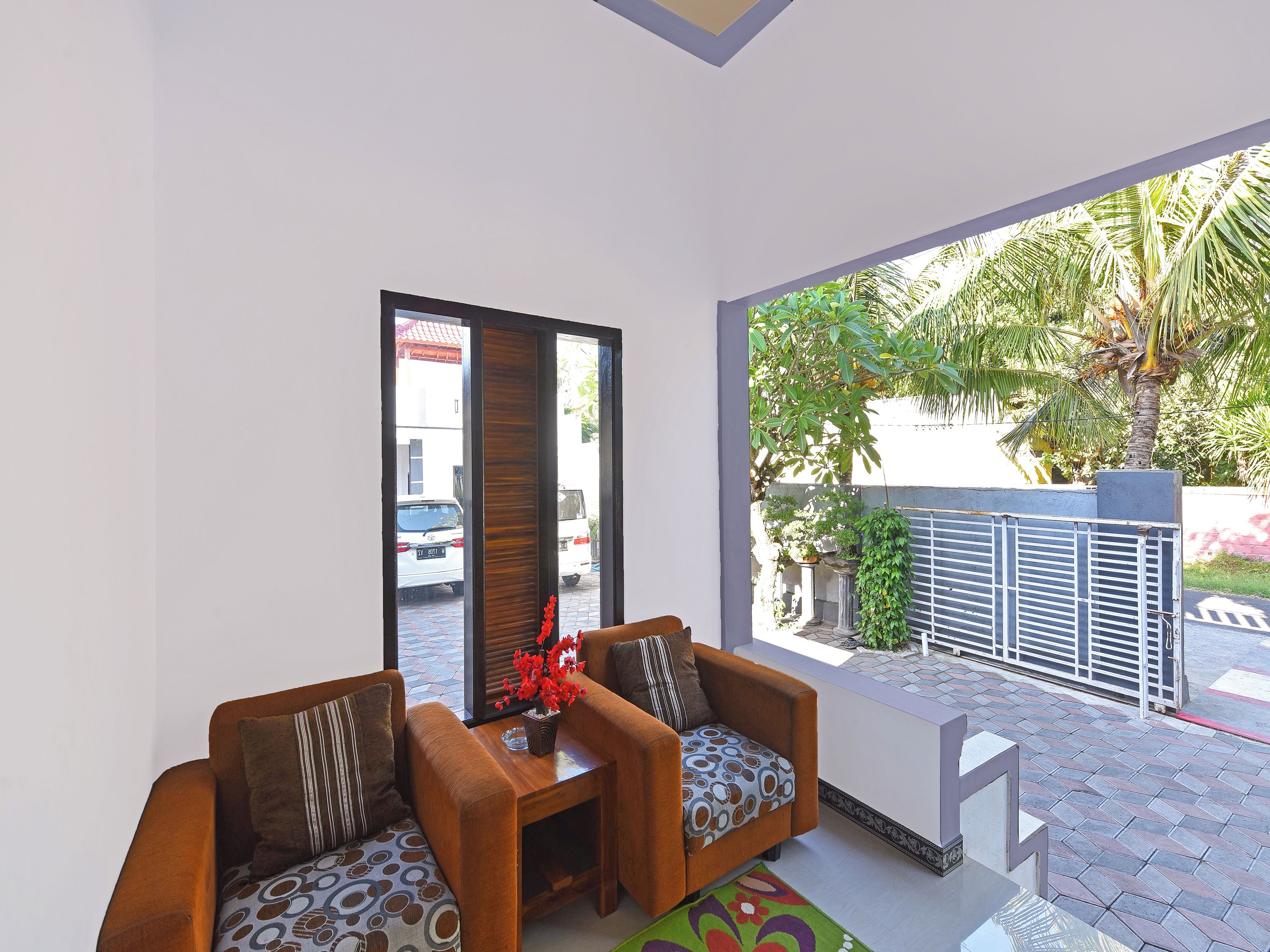 Una sala de estar moderna con dos sofás y una mesa de centro, ventanas amplias que dan a la calle y zonas verdes.