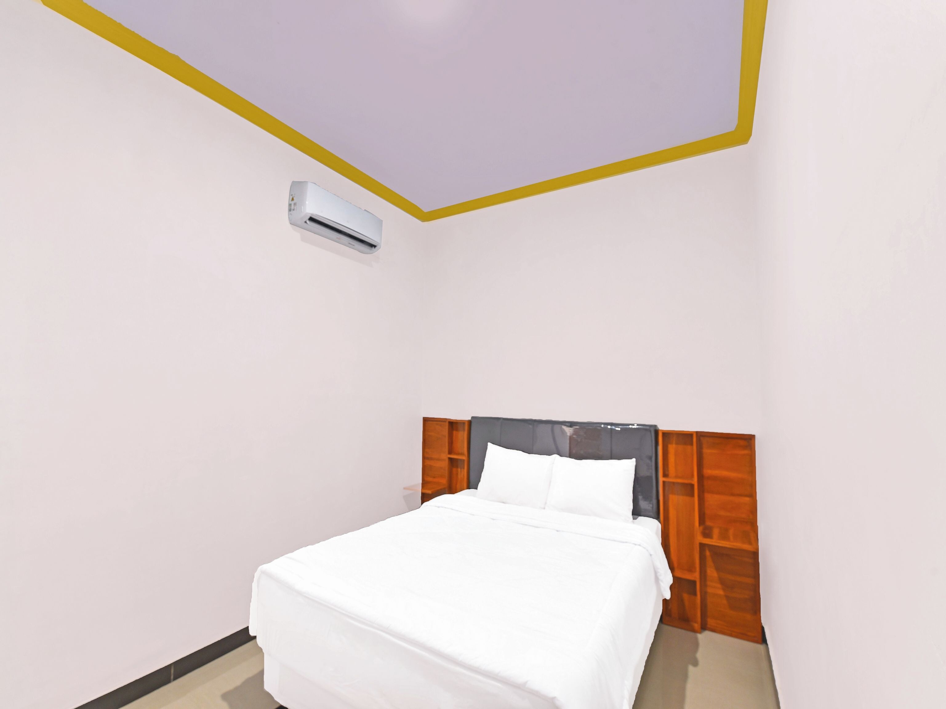 A bedroom with a bed, a wooden headboard, and an air conditioning unit.