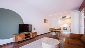 Een moderne woonkamer met een flatscreen televisie op een houten console, een ronde salontafel en een bruine bank.
