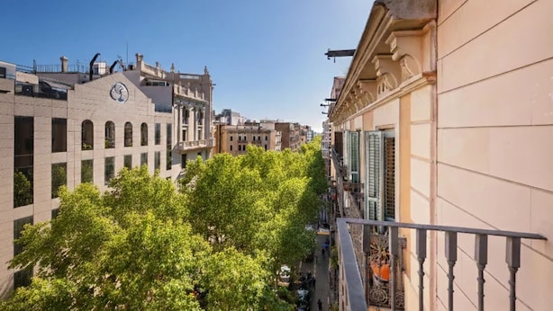 Eine schmale Stadtstraße mit traditioneller Architektur, darunter ein Gebäude mit einem Glockenturm und ein weiteres mit einem Balkon.