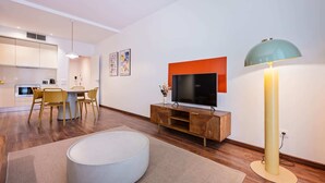 A modern living room with a flat-screen TV, a round ottoman, and a floor lamp. - Sweett | Bailen 401 - Two Bedroom Apartment, Sleeps 4 (Barcelona)