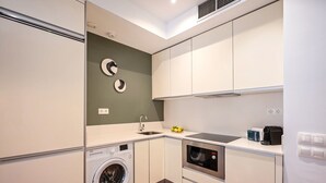 A compact kitchen with a washing machine, microwave, and a sink. - Sweett | Bailen 401 - Two Bedroom Apartment, Sleeps 4 (Barcelona)