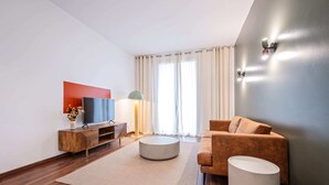 A modern living room with a flat-screen TV, a round coffee table, a sofa, and a lamp. - Sweett | Bailen 401 - Two Bedroom Apartment, Sleeps 4 (Barcelona)