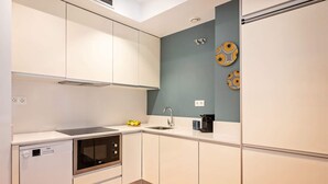 A compact kitchen with white cabinets, a built-in oven, a microwave, a sink, and a small countertop with a fruit bowl and a coffee maker. - Sweett | Bailen 404 - Two Bedroom Apartment, Sleeps 4 (Barcelona)