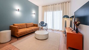 A modern living room with a sofa, a round coffee table, a chair, a TV, and a lamp. - Sweett | Bailen 404 - Two Bedroom Apartment, Sleeps 4 (Barcelona)