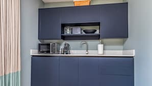 Una cucina moderna con pensili blu scuro, un piano di lavoro bianco, un lavello, una macchina da caffè e un forno a microonde.