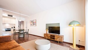 Uma sala de estar moderna com uma TV de tela plana, uma mesa de centro redonda e um sofá.