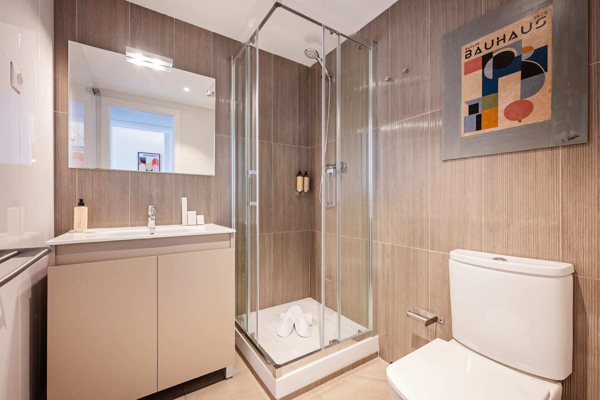 Une salle de bain moderne dotée d’une douche à parois de verre, de toilettes et d’un meuble-lavabo avec un miroir.