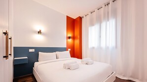 Una habitación de hotel moderna con una cama grande, una mesita de noche y una lámpara fijada a la pared.