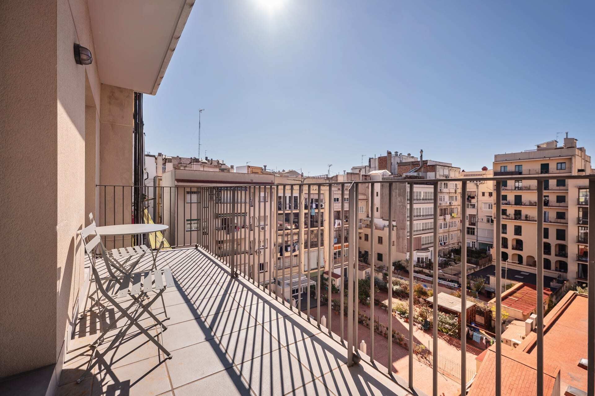 Un balcon doté d’une rambarde en métal, donnant sur un quartier résidentiel composé de plusieurs immeubles.