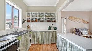 A kitchen with a window, a surfboard, and a dining area. - A-Wave from it All - 1960's Chic (Warrnambool)
