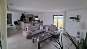 Una sala moderna con un sofá seccional, una mesa de centro y vistas a la cocina y el comedor.