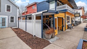 A row of colorful buildings with a covered outdoor seating area and a visible storefront.