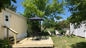 Un jardin avec une terrasse en bois, du mobilier d’extérieur et un espace salon abrité.
