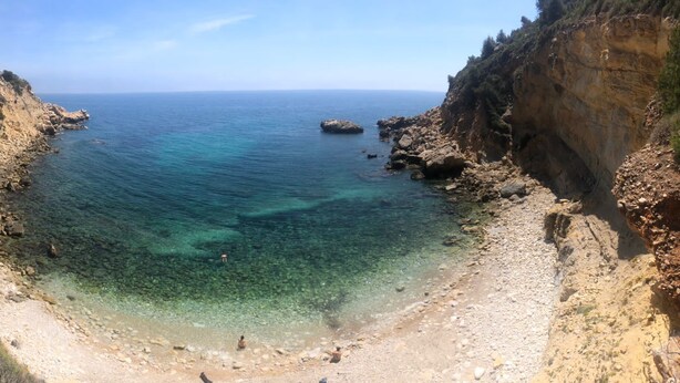 A coastal landscape with a rocky beach, clear water, and a cliff. - Gorgeous villa with swimming pool on the Costa Blanca, 800m away from the beach. (Moraira)