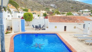 A swimming pool with a starfish decoration, surrounded by a white building with a tiled roof, and a view of a hillside with houses. - Gorgeous villa with swimming pool on the Costa Blanca, 800m away from the beach. (Moraira)