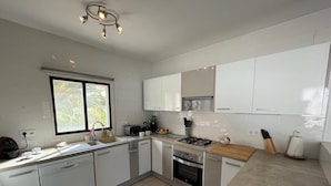 A modern kitchen with white cabinets, a gas stove, and a dishwasher. - Gorgeous villa with swimming pool on the Costa Blanca, 800m away from the beach. (Moraira)