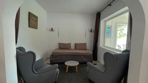 A compact living space with a bed, two armchairs, a small coffee table, and a window with a view. - Gorgeous villa with swimming pool on the Costa Blanca, 800m away from the beach. (Moraira)