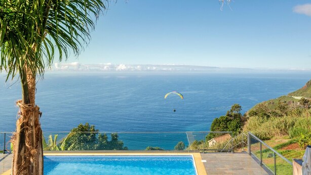 A pool with a view of the ocean and a person paragliding in the distance. - Quality tranquil villa with sea-view | OceanScape (Poiso)