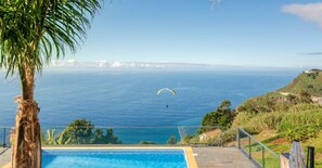 A pool with a view of the ocean and a person paragliding in the distance. - Quality tranquil villa with sea-view | OceanScape (Poiso)
